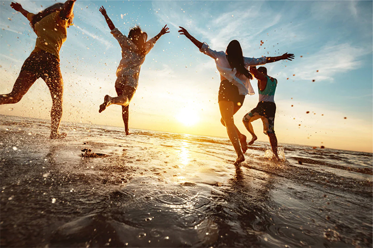 People jumping on the beach at sunset