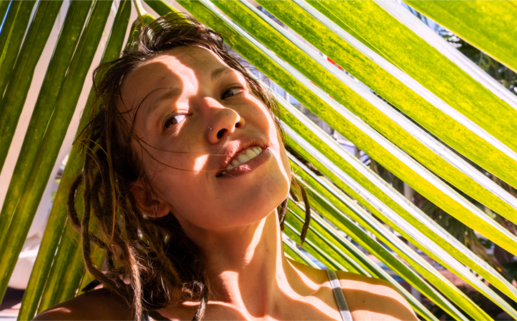 Face partially shaded by palm leaves